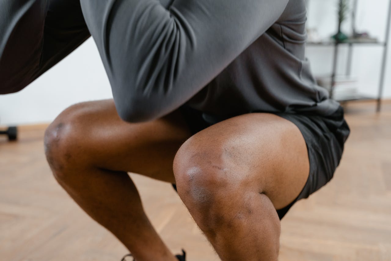 A focused view of a male athlete performing squats in a gym setting, emphasizing fitness and strength.